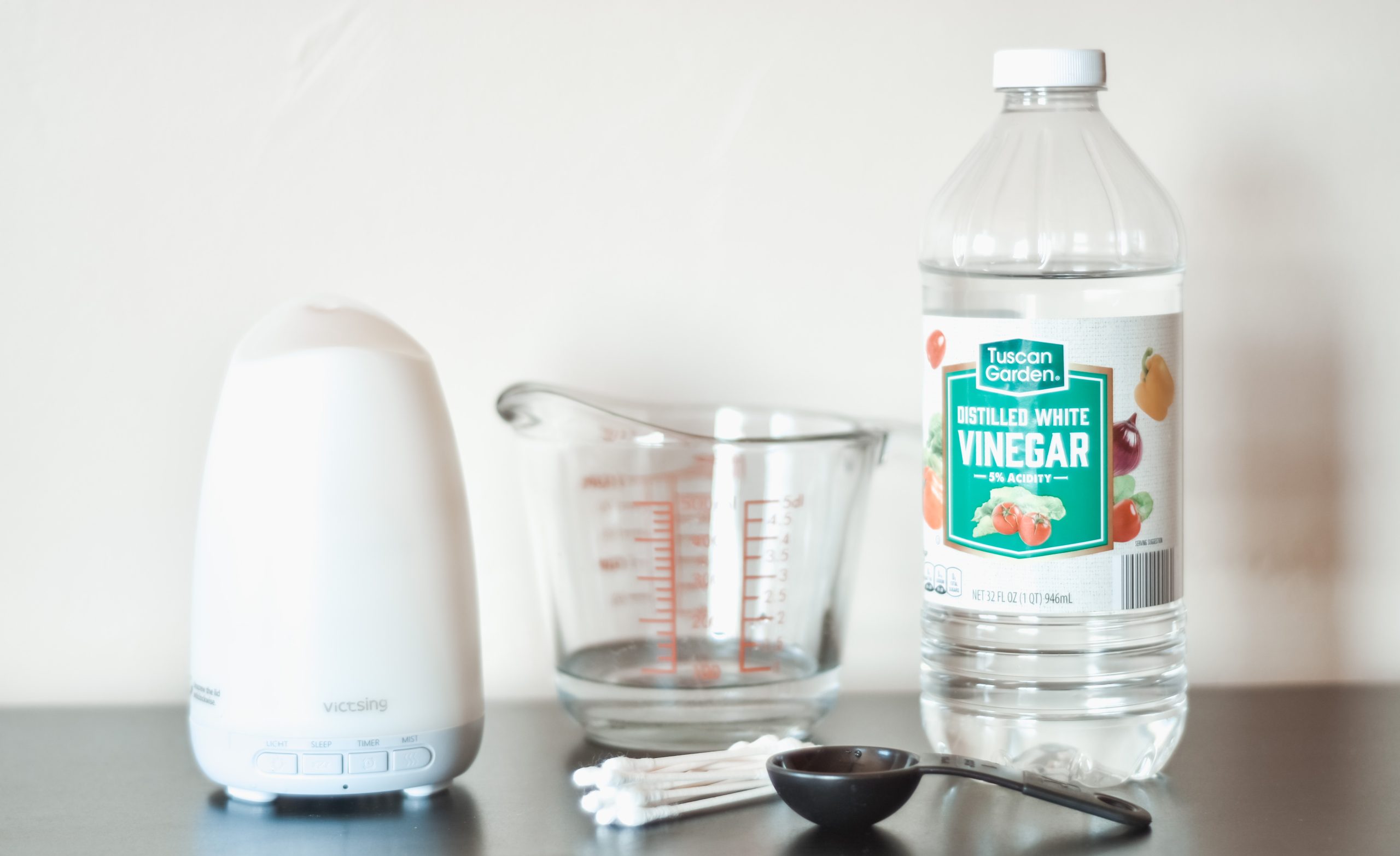 Vinegar, glass measuring cup, q-tips, essential oil diffuser